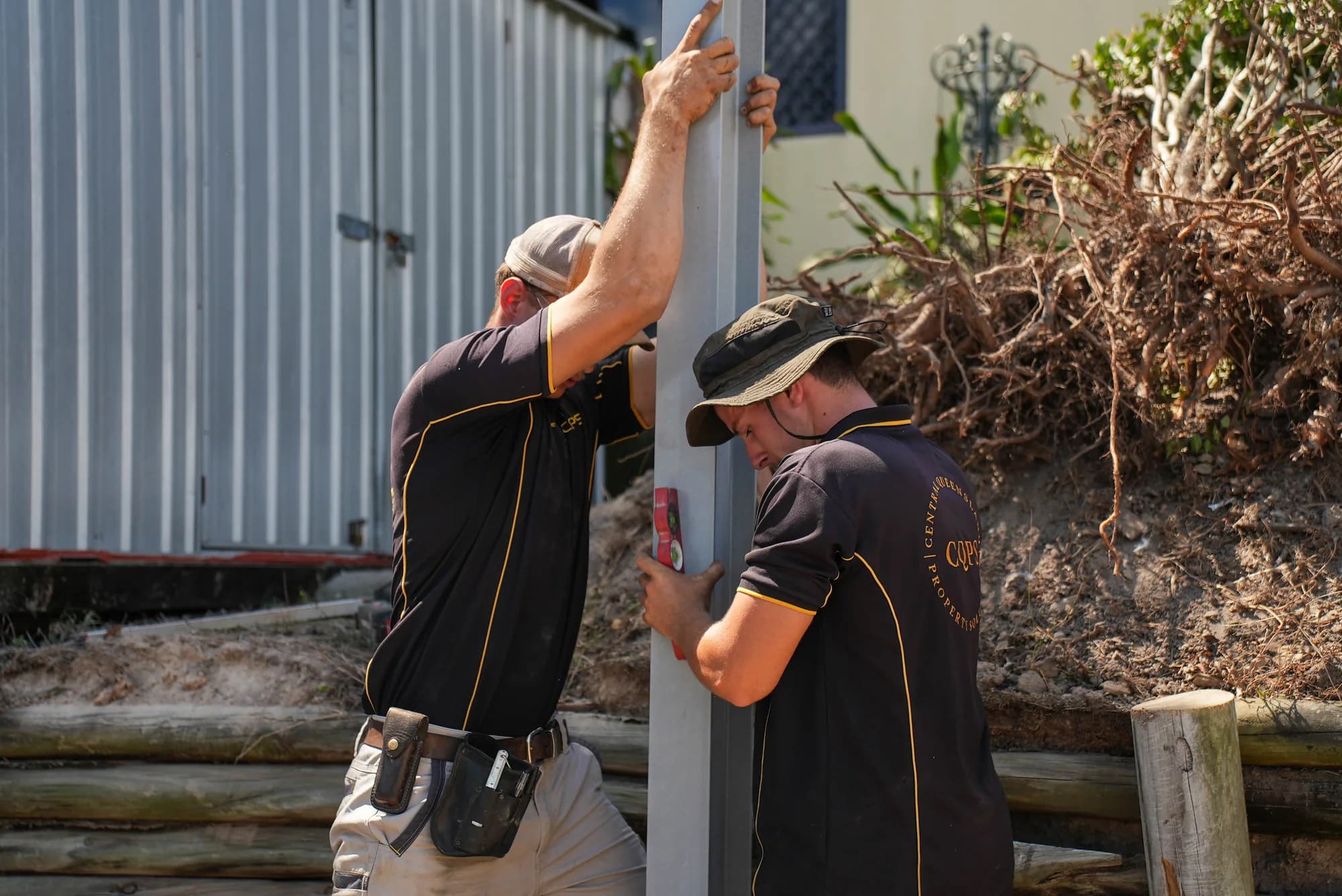 Two CQPS team members aligning a retaining wall post
