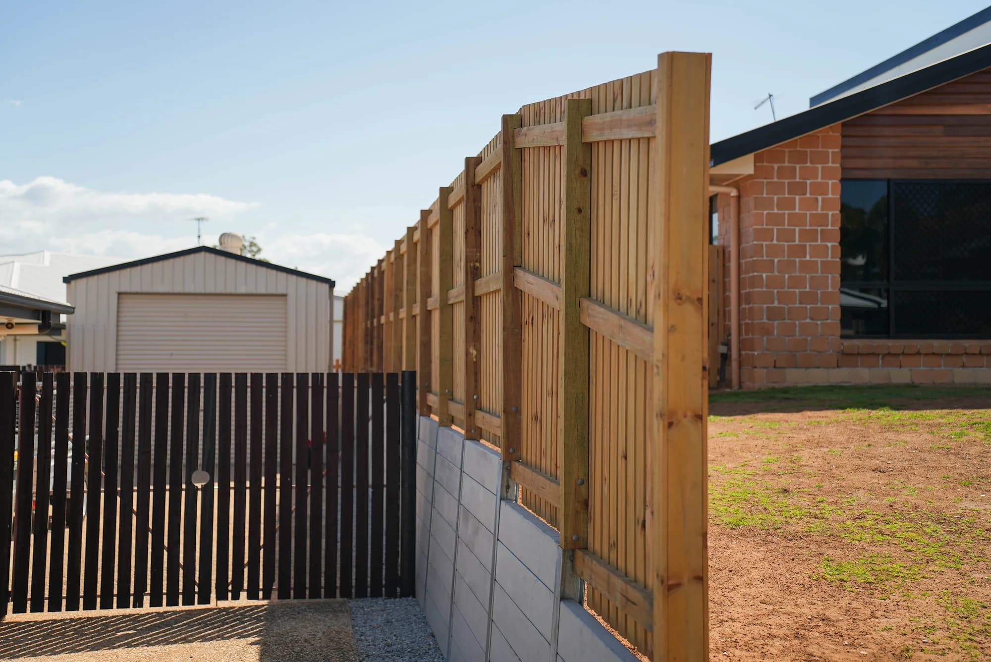 Timber gate beside a concrete sleeper retaining wall