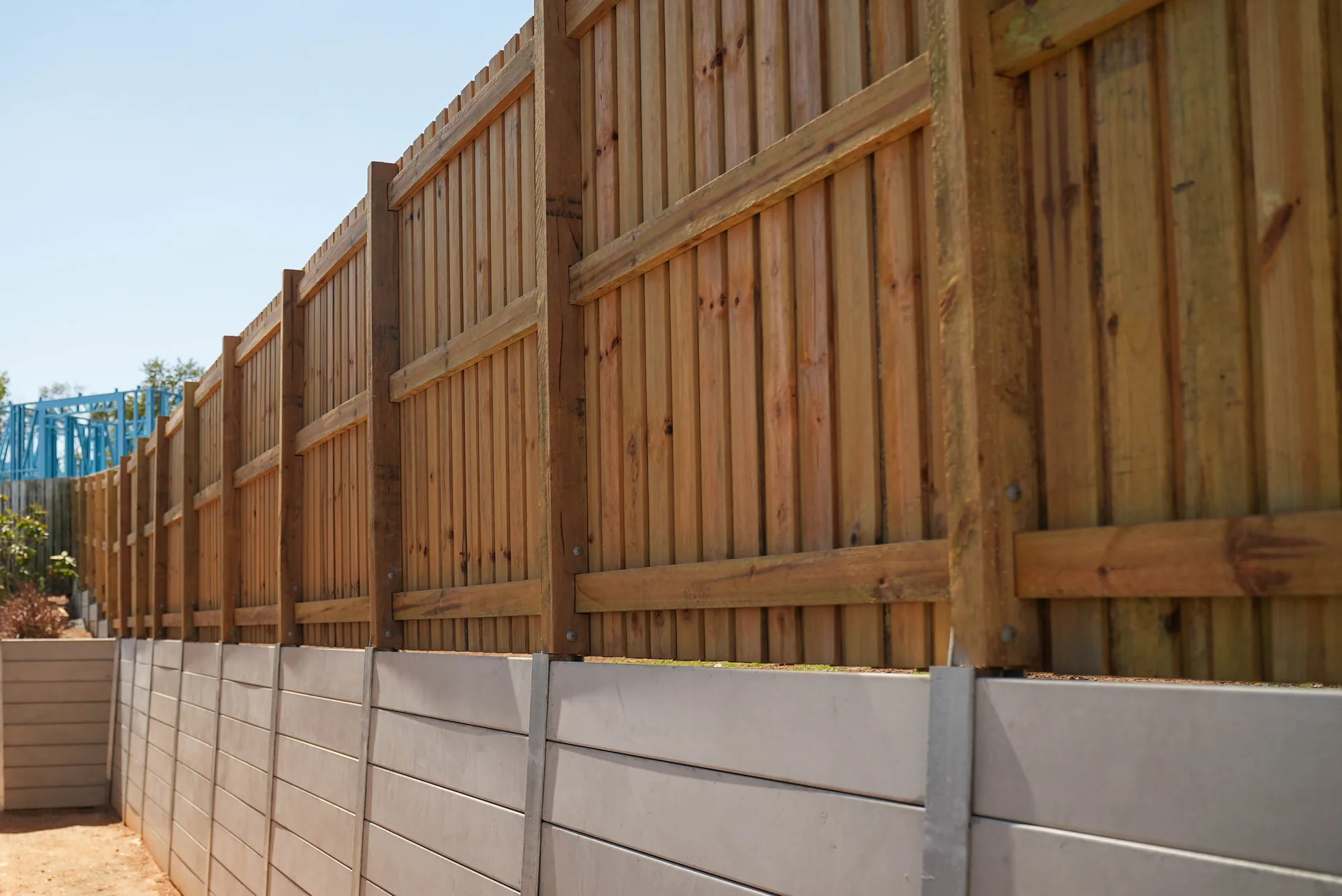 Timber fence above a concrete sleeper retaining wall